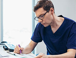 Male nurse filling out form while at a desk