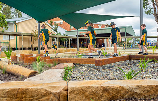 Children play beneath large green shadesails