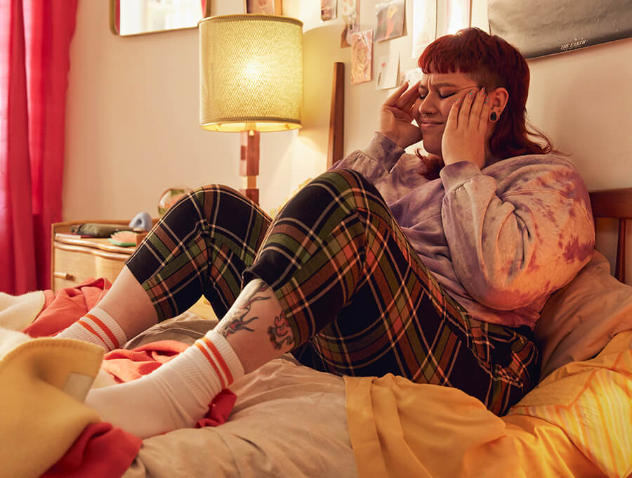 A young woman sits on her bed experiencing withdrawal symptoms from vaping
