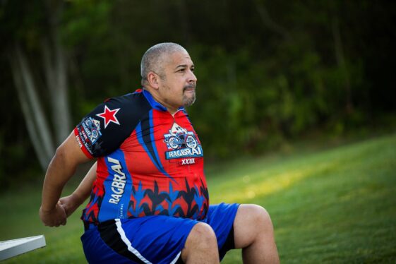 Older man in rugby gear stretches while sitting on a bench