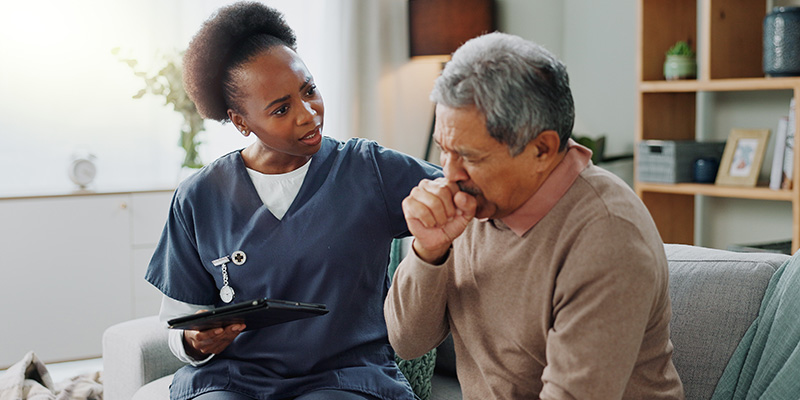 a nurse talks with a patient while holding a tablet