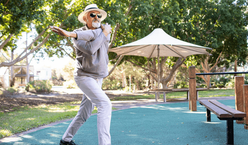 An elderly man stretches in a park before going for his run.