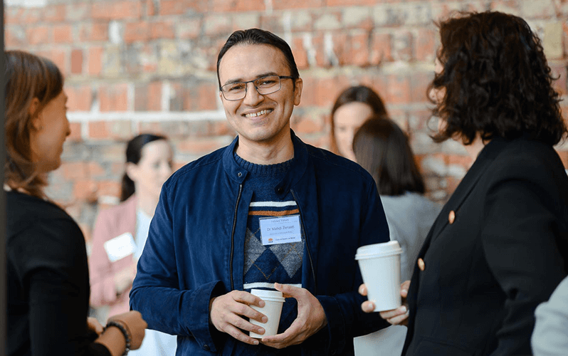 A NSW cancer researcher at a Cancer Institute NSW event smiling at the camera while talking to peers