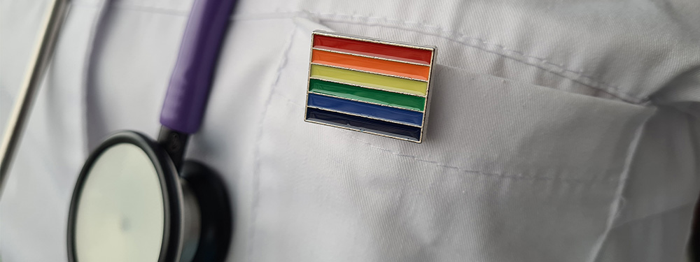 Close up of a rainbow badge pinned to a labcoat